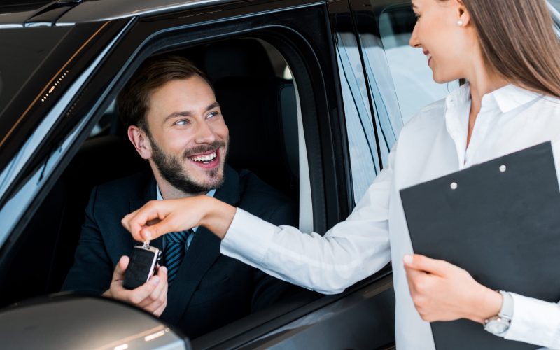 selective focus of attractive woman giving car key to happy man in car selective focus of attractive woman giving car key to happy man in car